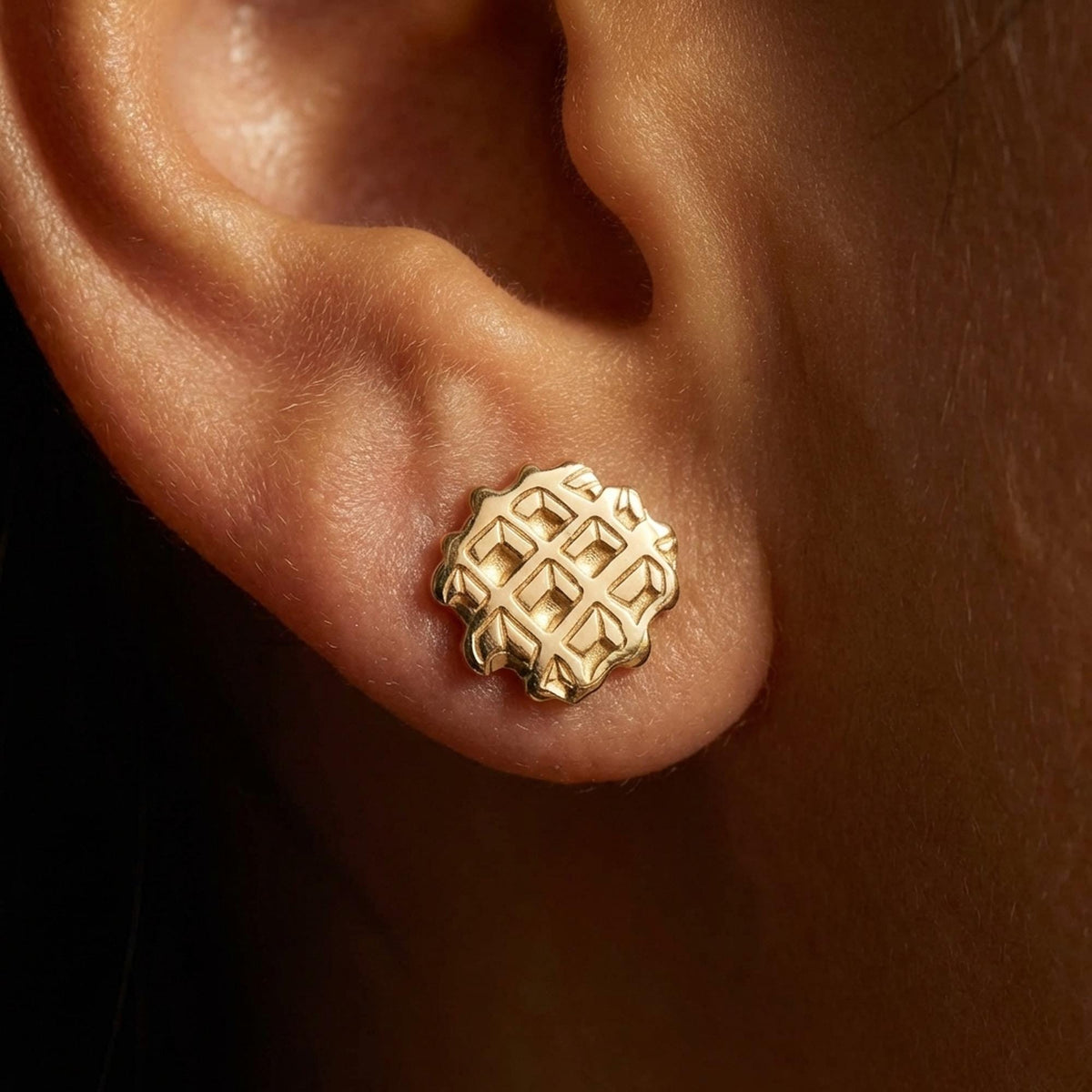 Pair of small gold waffle stud earrings with a square grid texture, shown front on