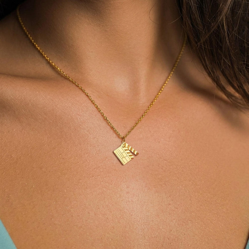 Flat gold film clapboard pendant with a striped hinged arm on a fine chain. (2 of 6)