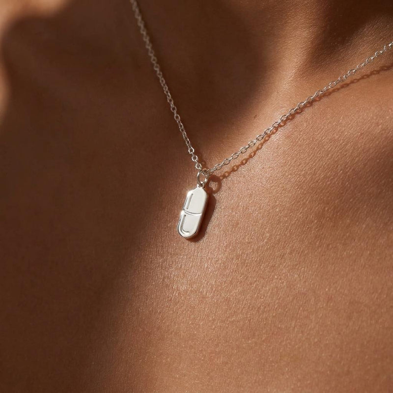 Small gold pill capsule pendant hanging from a fine cable chain. (2 of 9)
