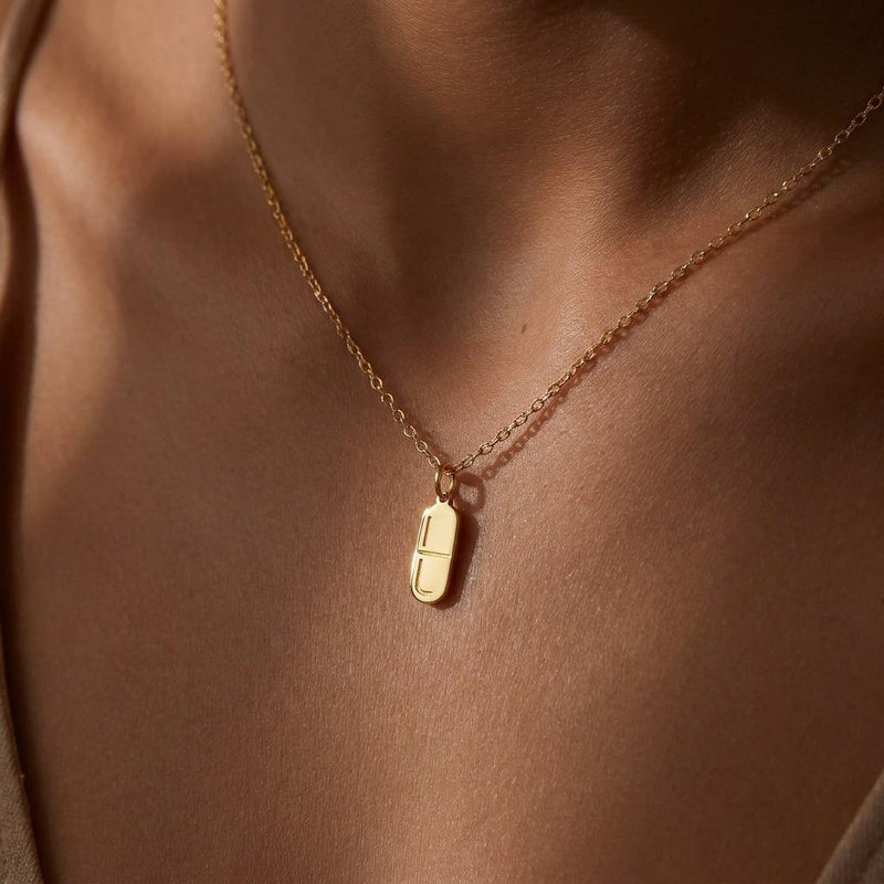 Small gold pill capsule pendant hanging from a fine cable chain. (3 of 9)
