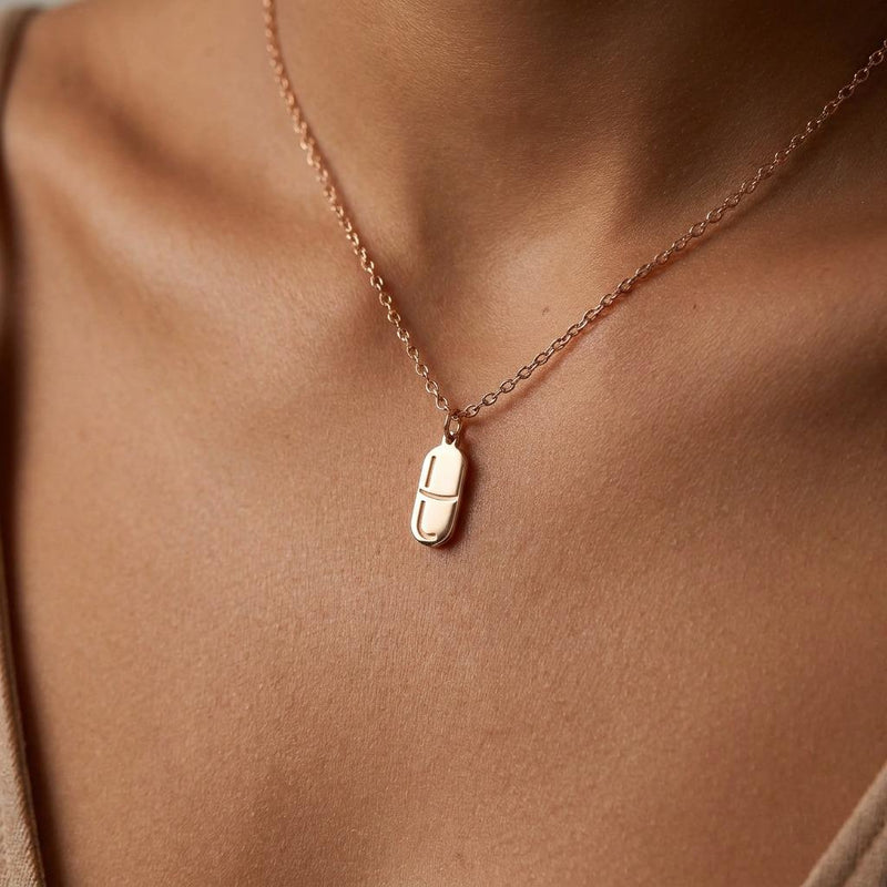 Small gold pill capsule pendant hanging from a fine cable chain. (4 of 9)