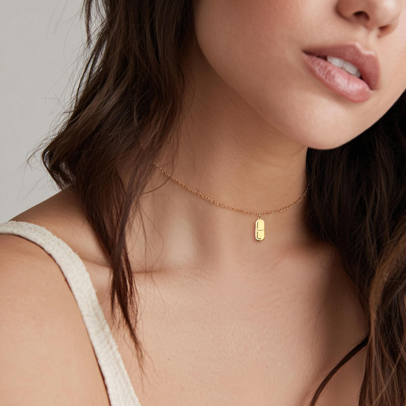 Small gold pill capsule pendant hanging from a fine cable chain. (5 of 9)