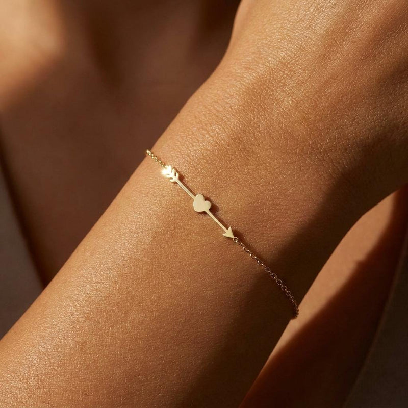 Fine gold chain bracelet with a flat heart and arrow charm