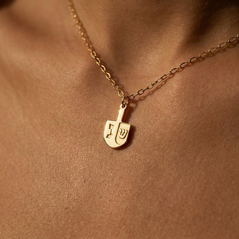 Small dreidel pendant on a thin gold cable chain necklace