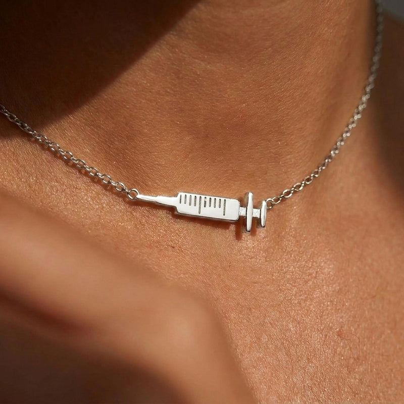 Slim gold syringe pendant with plunger and needle hanging from a thin chain (4 of 9)