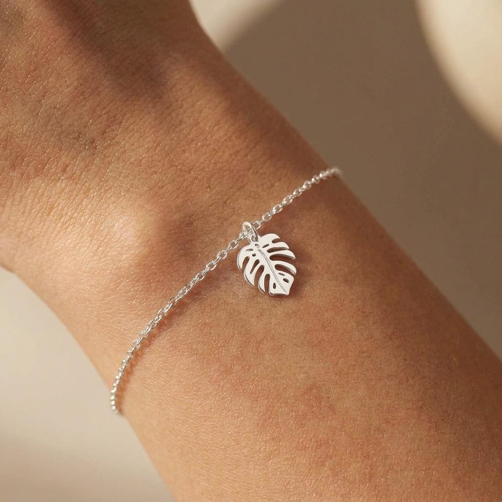 Fine gold chain bracelet with a small split monstera leaf charm (2 of 8)