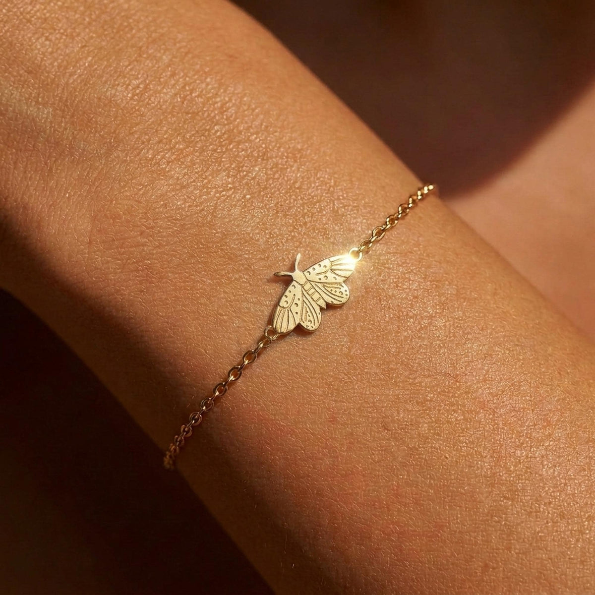 Fine gold chain bracelet with a tiny spread wing moth charm