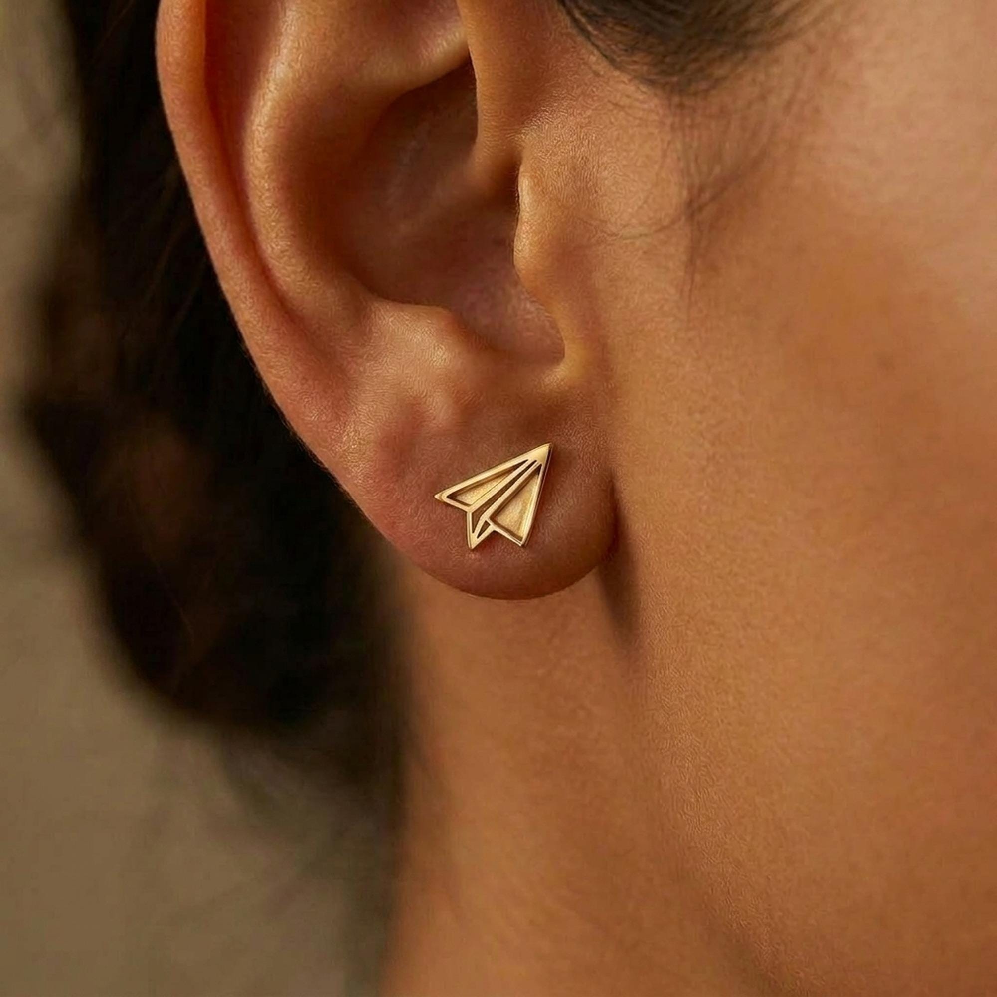 Tiny gold paper airplane stud earrings with cut fold lines, shown as a pair (2 of 7)
