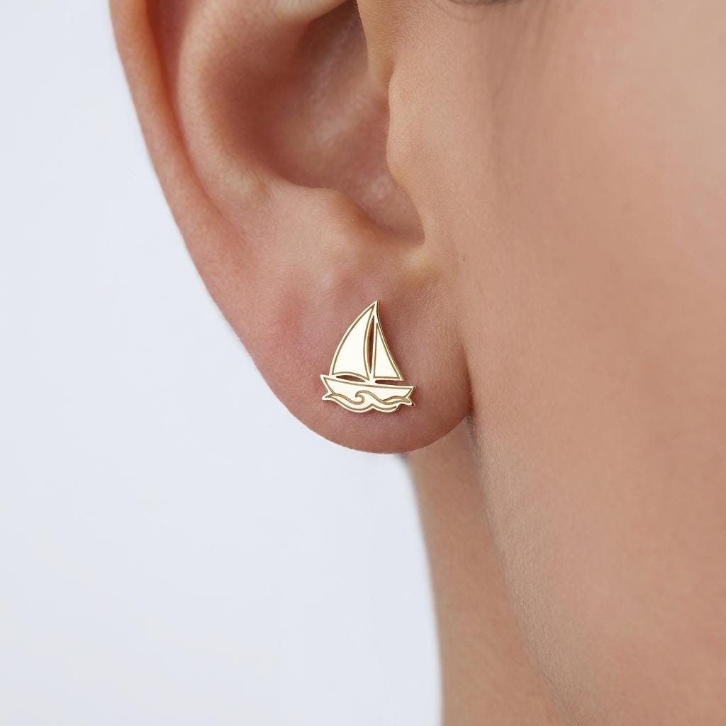 Pair of tiny gold sailboat stud earrings on a white background. (2 of 9)