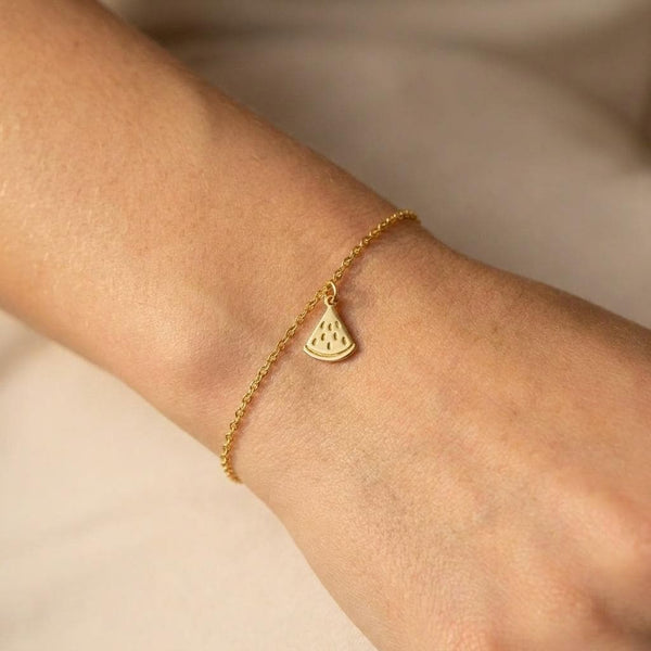 Tiny watermelon slice charm in gold on a fine cable chain bracelet with lobster clasp