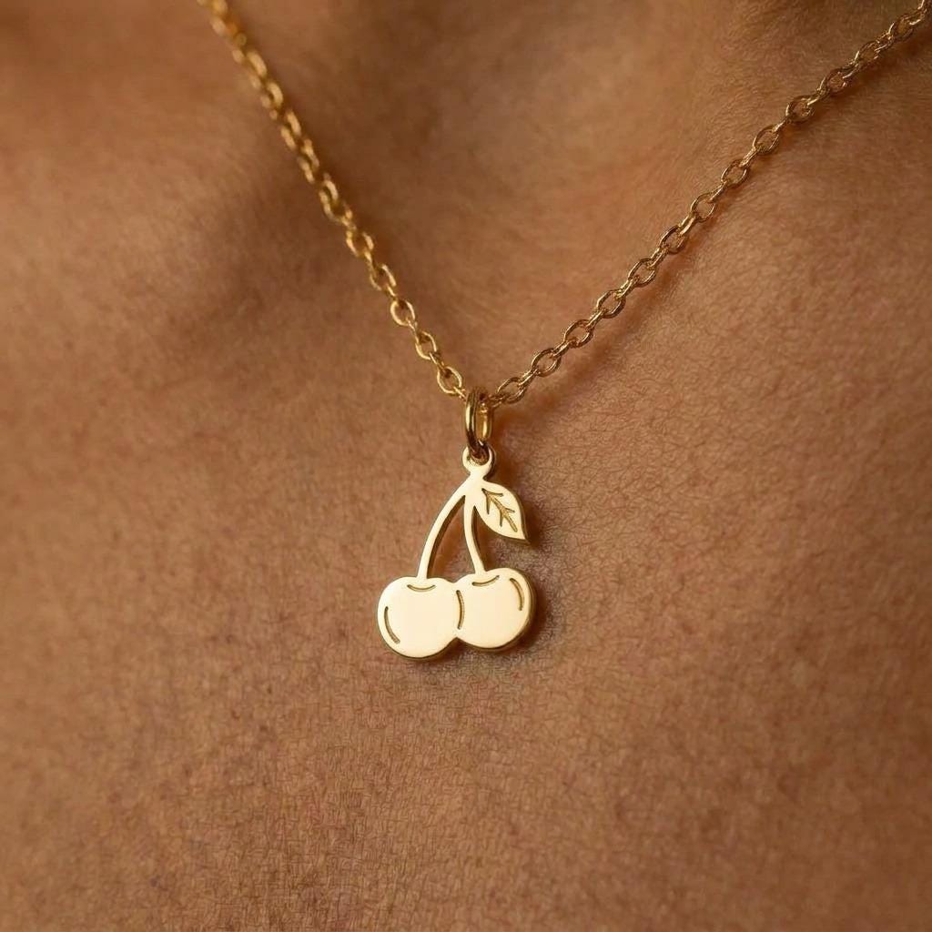 Small gold cherry pair pendant with a curved stem hanging from a fine cable chain