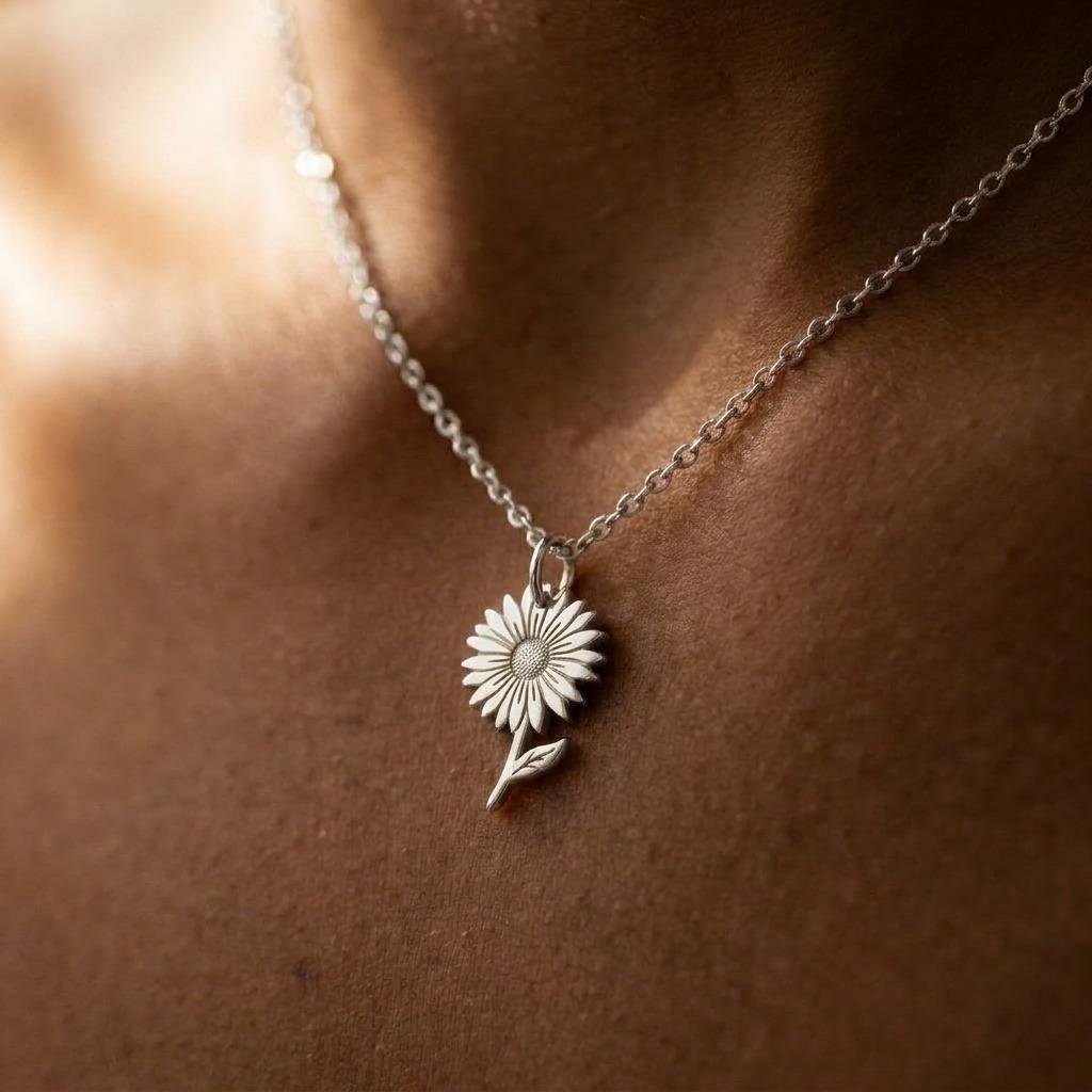 Fine gold chain necklace with an open daisy flower pendant on a plain background (2 of 7)
