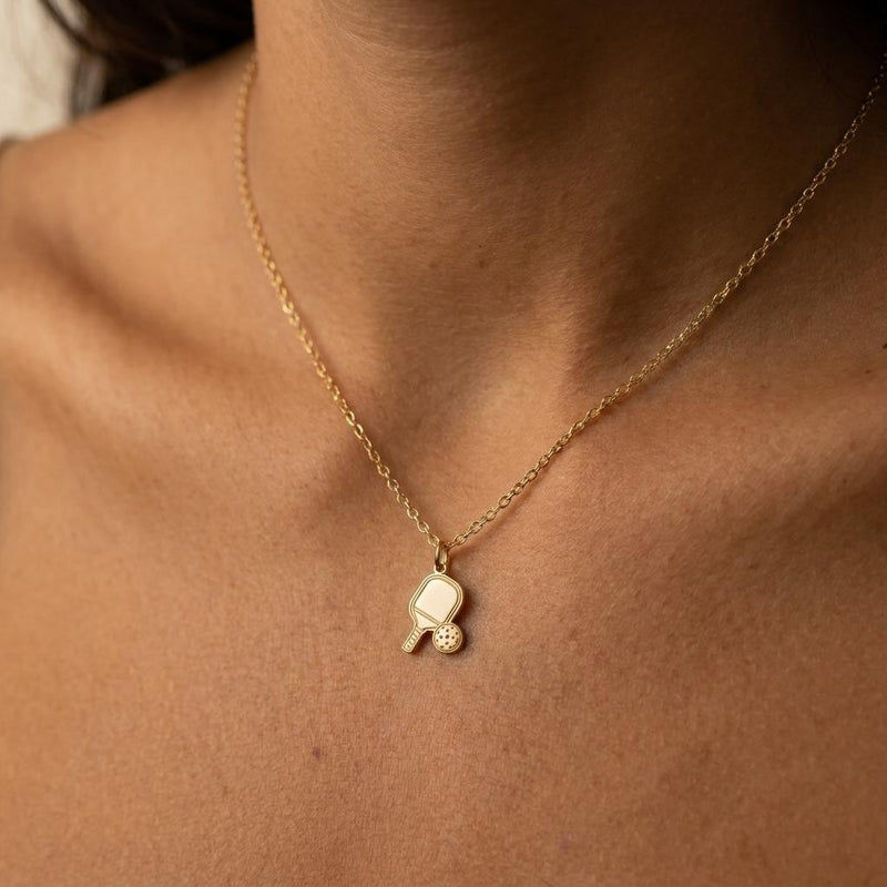 Small gold pickleball paddle pendant with perforated ball beside it on a chain (2 of 7)