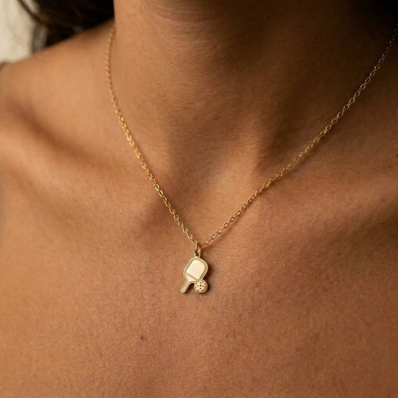Small gold pickleball paddle pendant with perforated ball beside it on a chain (4 of 7)