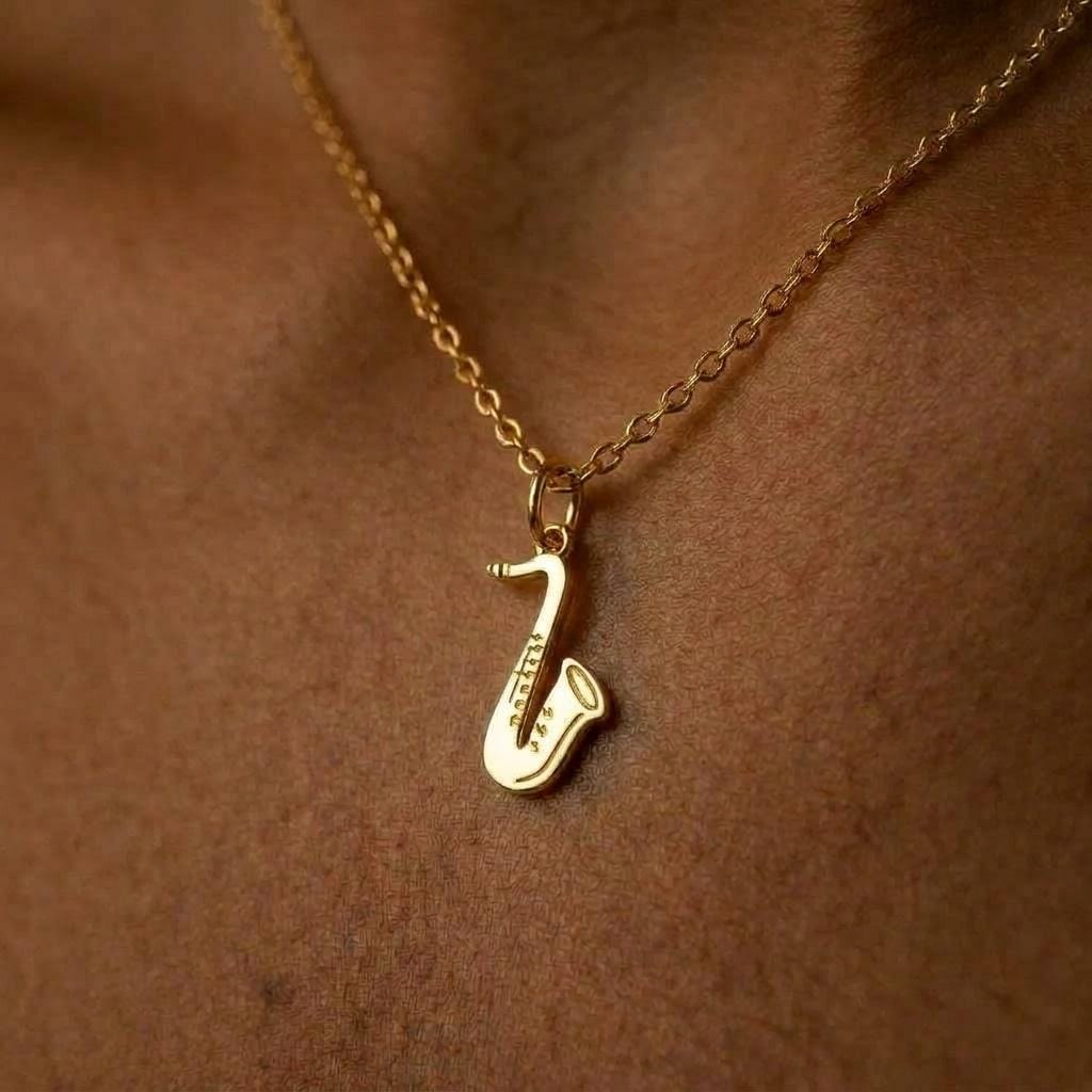 Fine gold chain necklace with a saxophone pendant shown in profile
