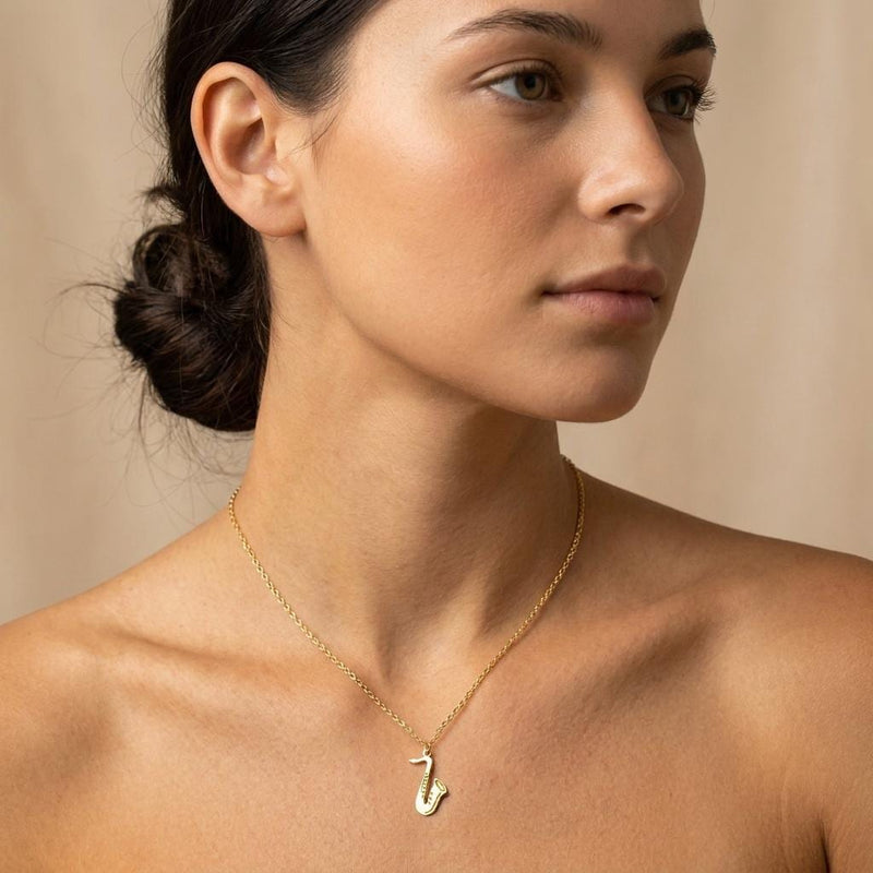Fine gold chain necklace with a saxophone pendant shown in profile (2 of 8)