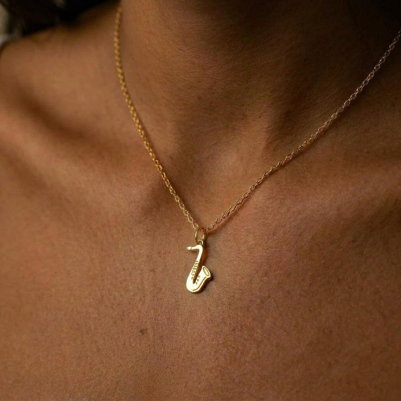 Fine gold chain necklace with a saxophone pendant shown in profile (5 of 8)