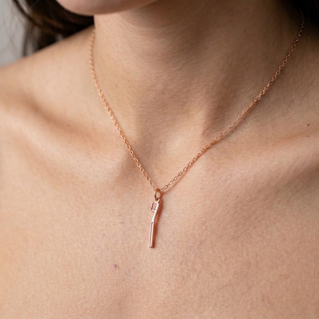 Small gold toothbrush pendant with bristle head lying flat on a thin chain (2 of 7)