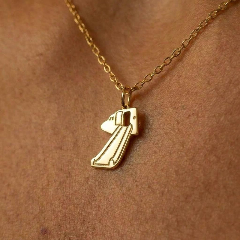 Gold pendant shaped like a deployed aircraft evacuation slide on a fine chain