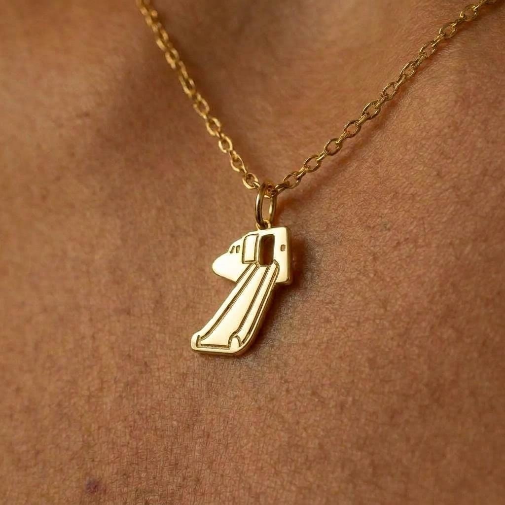 Gold pendant shaped like a deployed aircraft evacuation slide on a fine chain