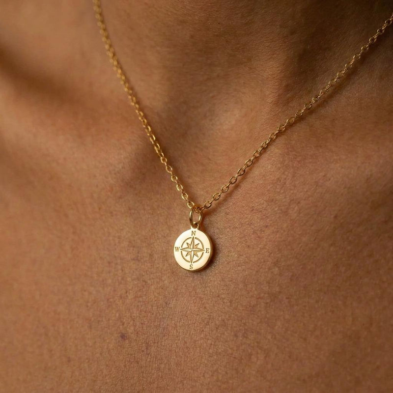 Tiny gold compass pendant with needle detail on a fine cable chain