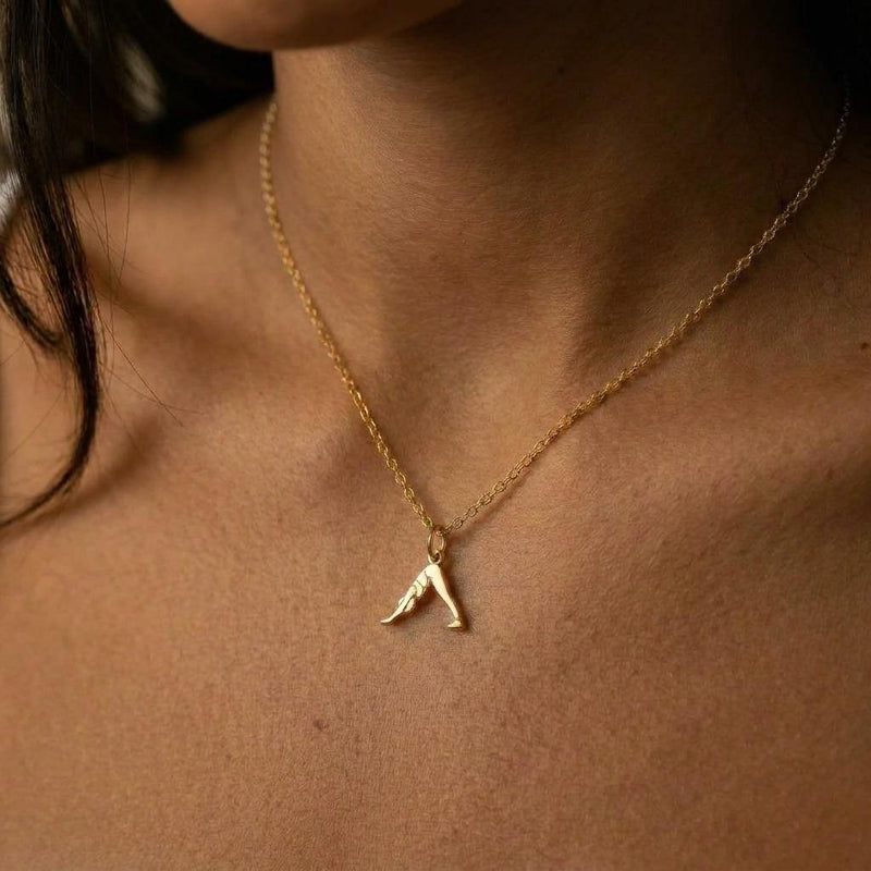 Small gold pendant of a figure in downward dog pose on a fine chain, white background. (3 of 8)