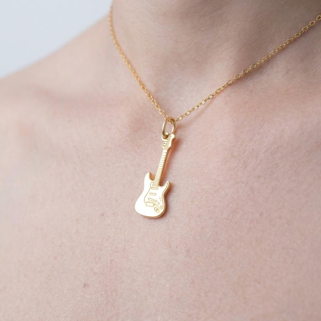 Tiny gold electric guitar pendant hanging from a fine cable chain on a white background. (2 of 9)