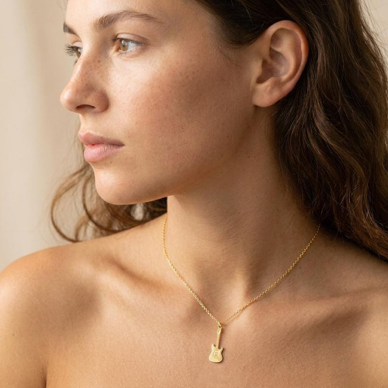 Tiny gold electric guitar pendant hanging from a fine cable chain on a white background. (3 of 9)