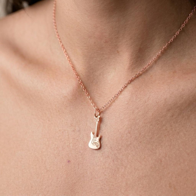 Tiny gold electric guitar pendant hanging from a fine cable chain on a white background. (5 of 9)