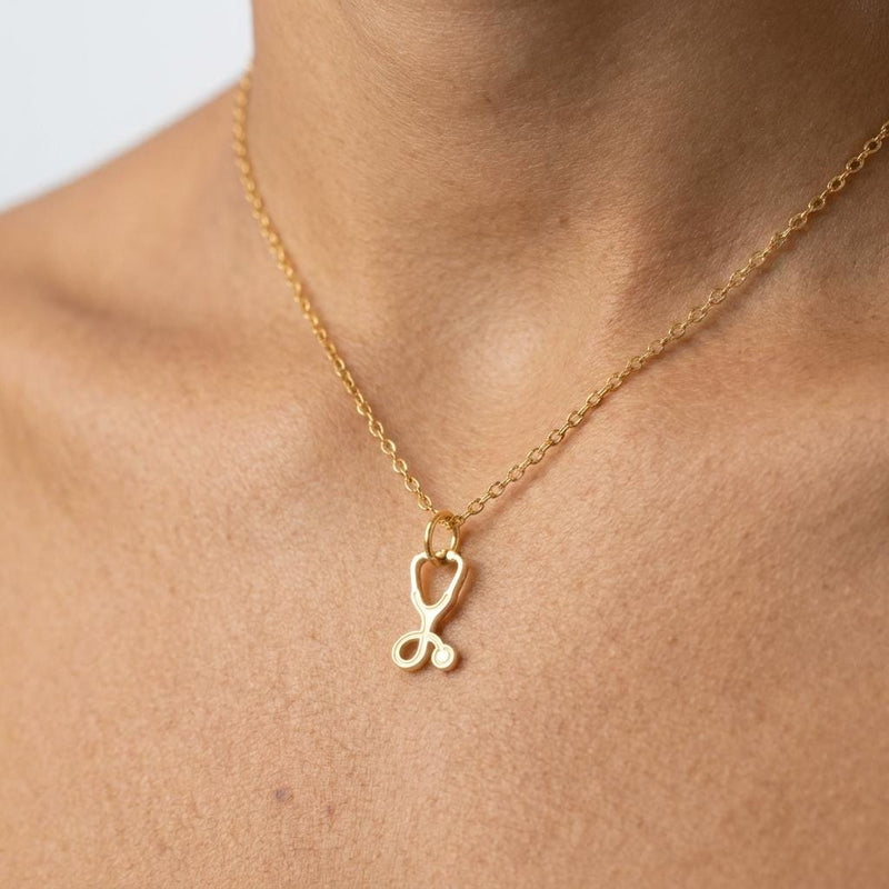 Gold stethoscope charm necklace with looped tubing and bell, on a fine chain