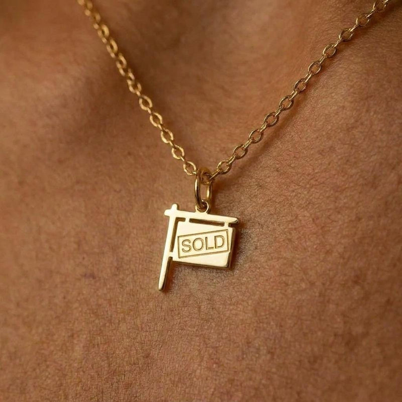 Gold yard sign charm necklace reading SOLD, on a fine cable chain