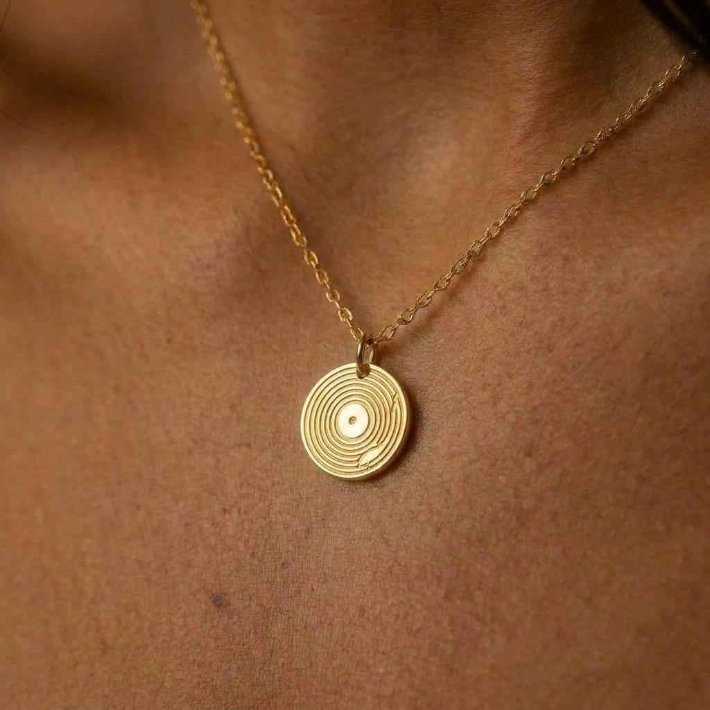 Small gold vinyl record pendant with grooves on a fine cable chain
