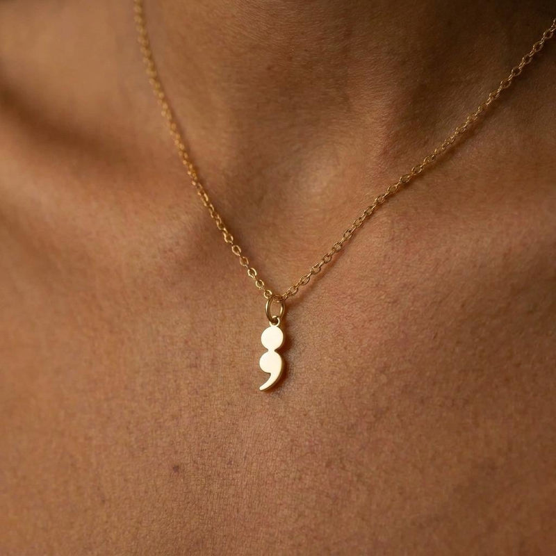 Fine gold chain necklace with a small semicolon shaped pendant