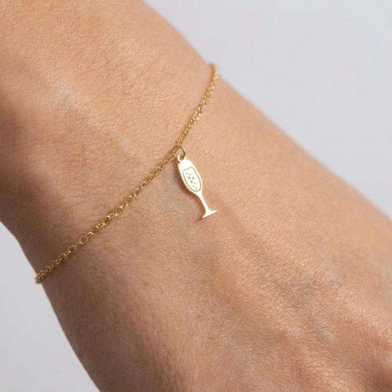 Fine gold chain bracelet with a slim champagne flute charm