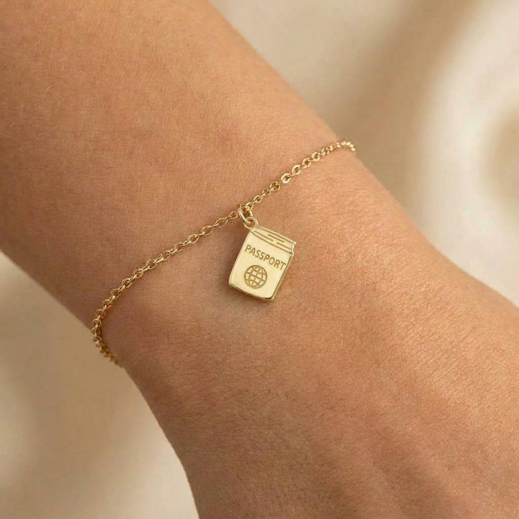 Tiny gold passport charm on a fine bracelet chain with clasp, white background. (2 of 5)