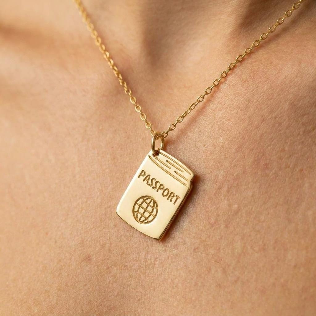 Tiny gold passport pendant on a fine cable chain against a white background. (2 of 5)