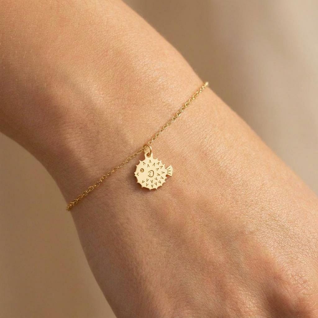 Fine gold chain bracelet with a small round puffer fish charm