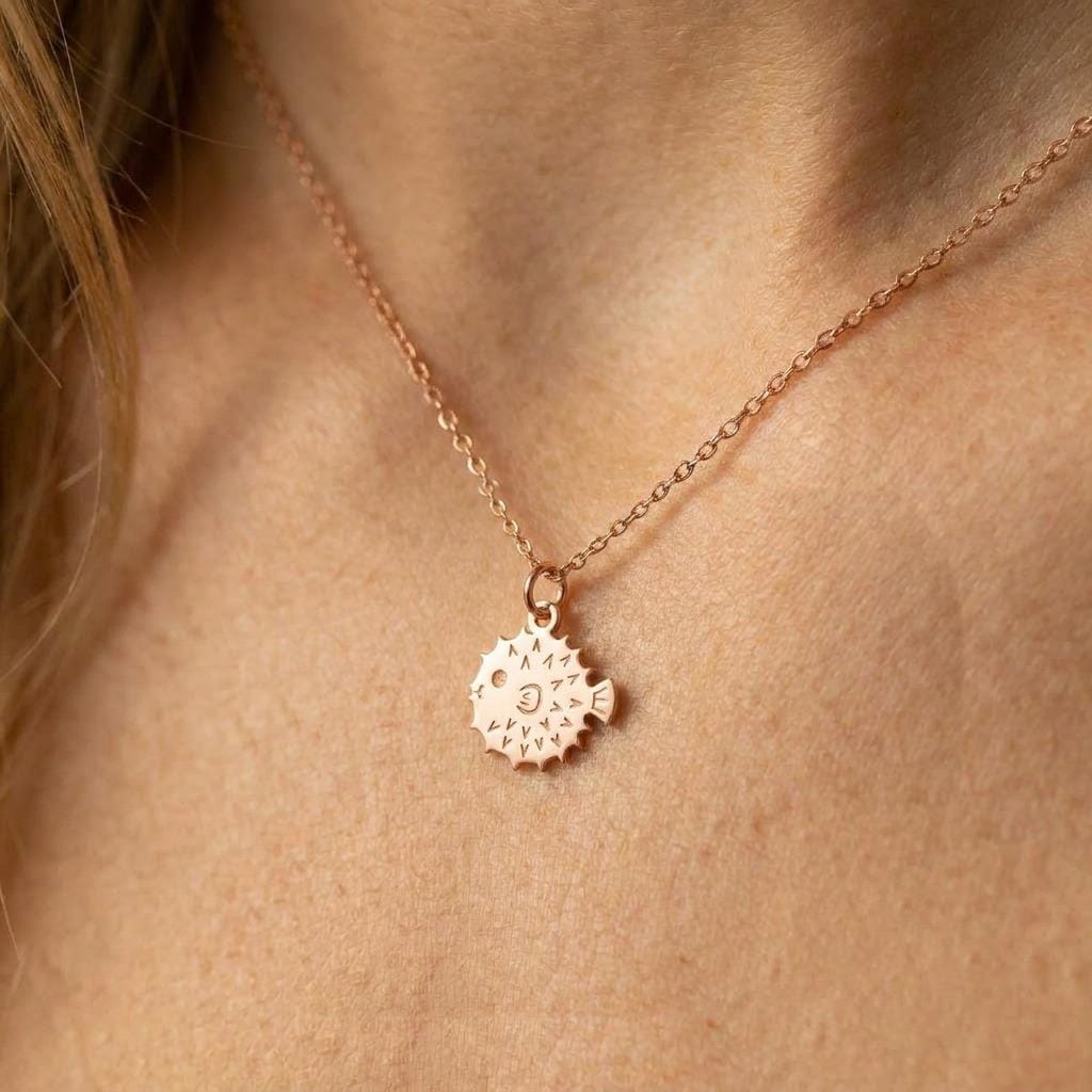 Small round gold puffer fish pendant with spines, on a fine cable chain