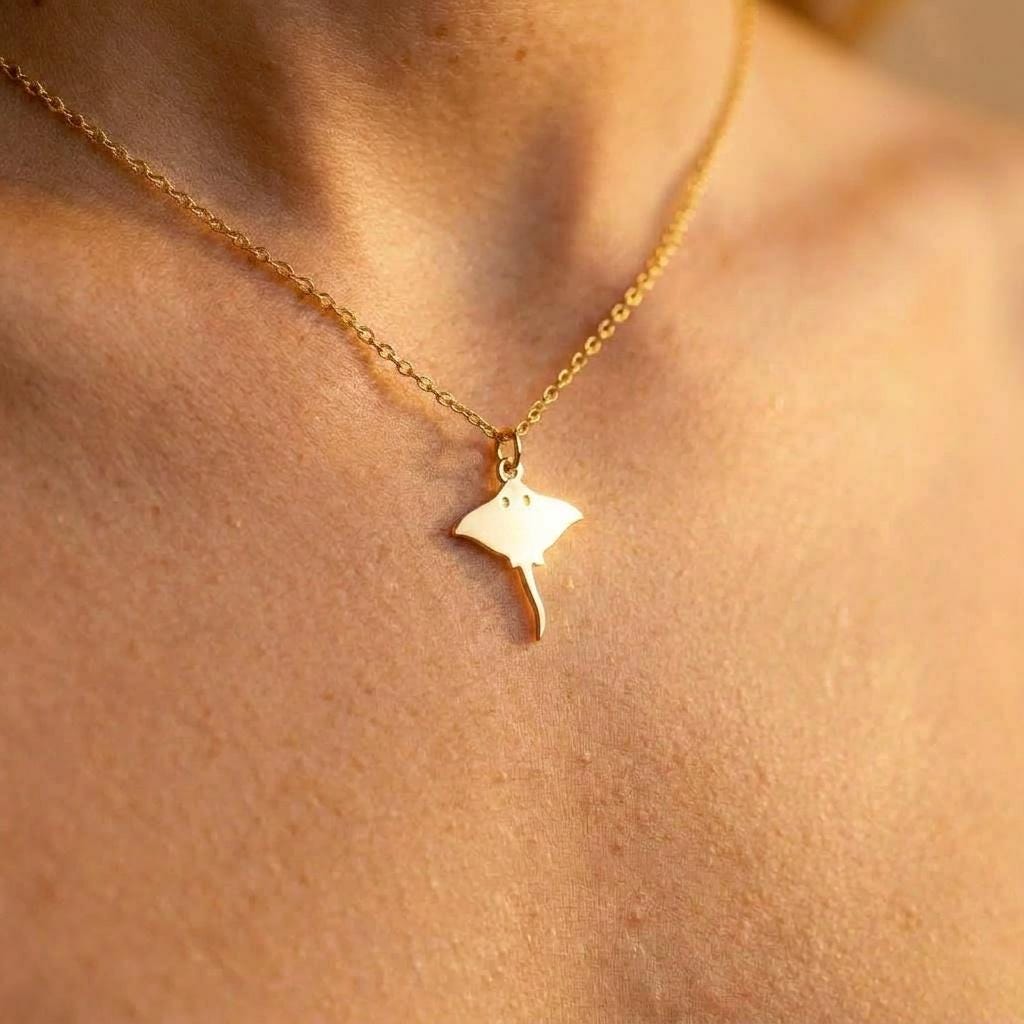 Small gold stingray pendant with flared wings and long tail on a fine chain