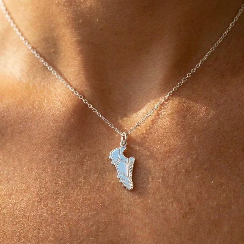 Small gold soccer cleat pendant hanging from a fine gold chain on a white background (3 of 8)