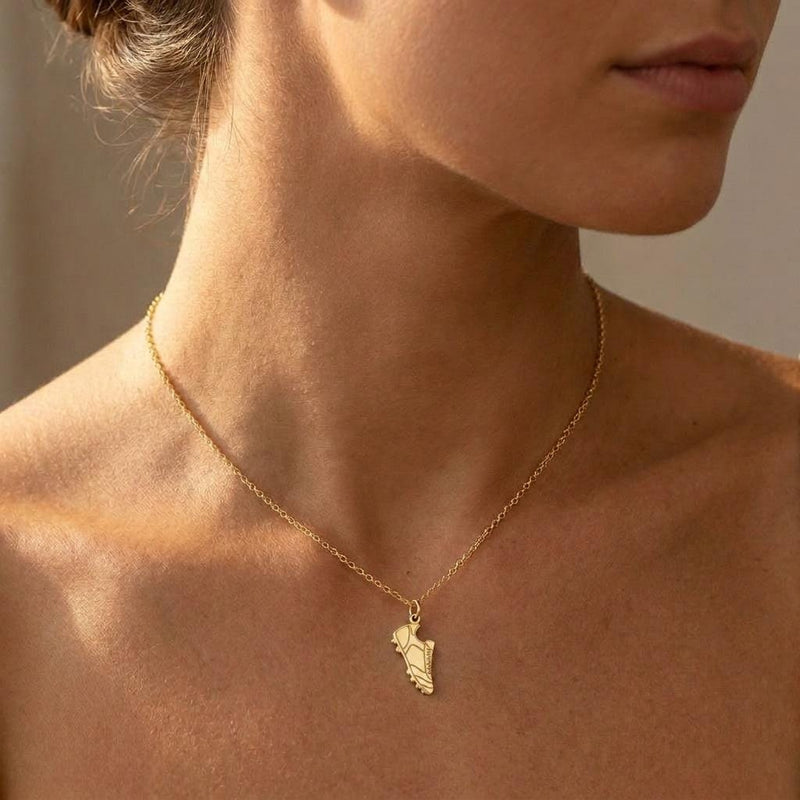 Small gold soccer cleat pendant hanging from a fine gold chain on a white background (5 of 8)