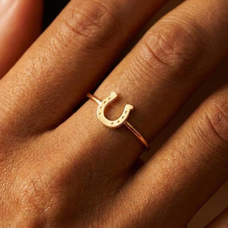 Dainty gold horseshoe ring with a thin band and a small sculpted horseshoe across the top