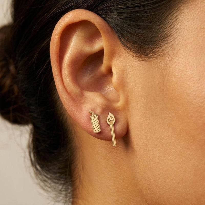 Mismatched gold earrings, a struck match on one side and a firecracker with a fuse on the other (3 of 8)