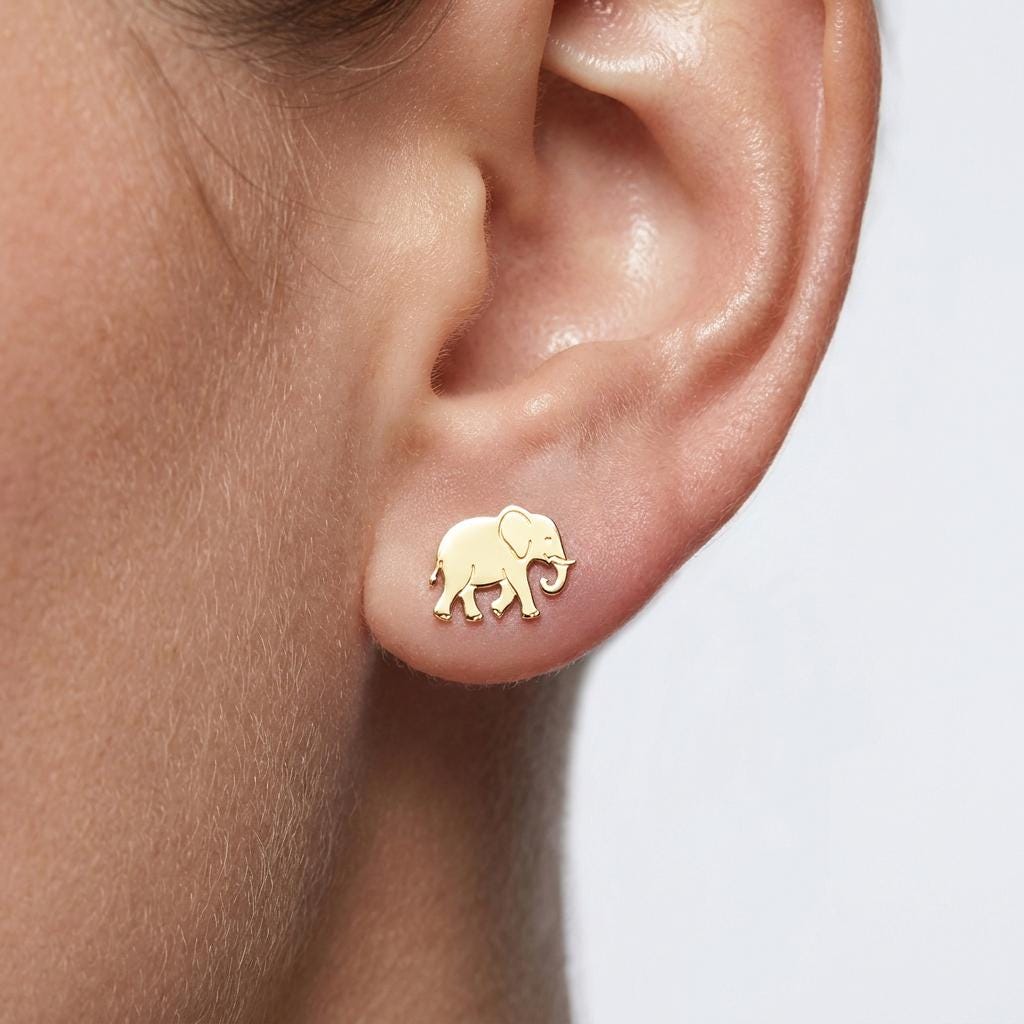 Pair of tiny gold elephant stud earrings with raised trunk, shown on a white background (2 of 5)