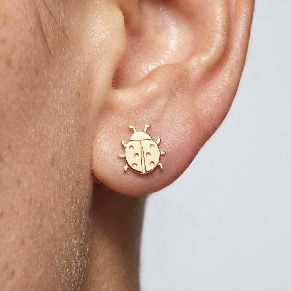 Pair of tiny gold ladybug stud earrings with rounded wings and spots, on plain posts. (2 of 7)