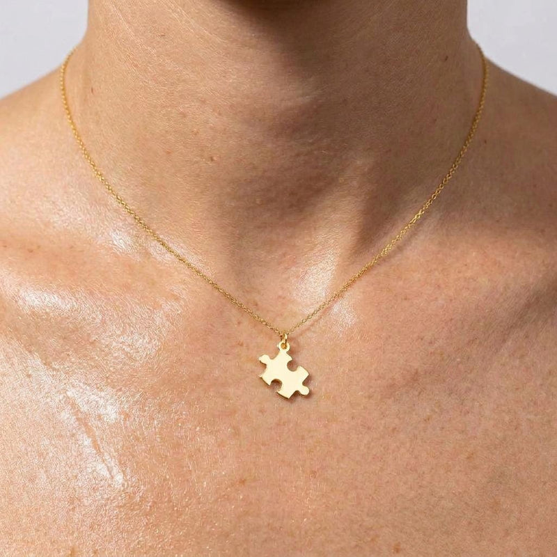 Small gold puzzle piece pendant on a thin cable chain necklace