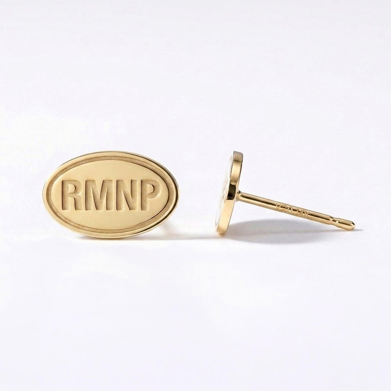 Pair of small gold oval stud earrings showing mountain peaks and evergreen trees