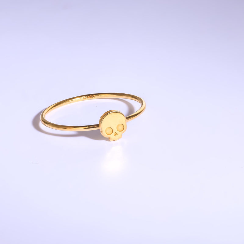 Thin gold ring set with a small skull charm with cut eye sockets and a grin (7 of 11)
