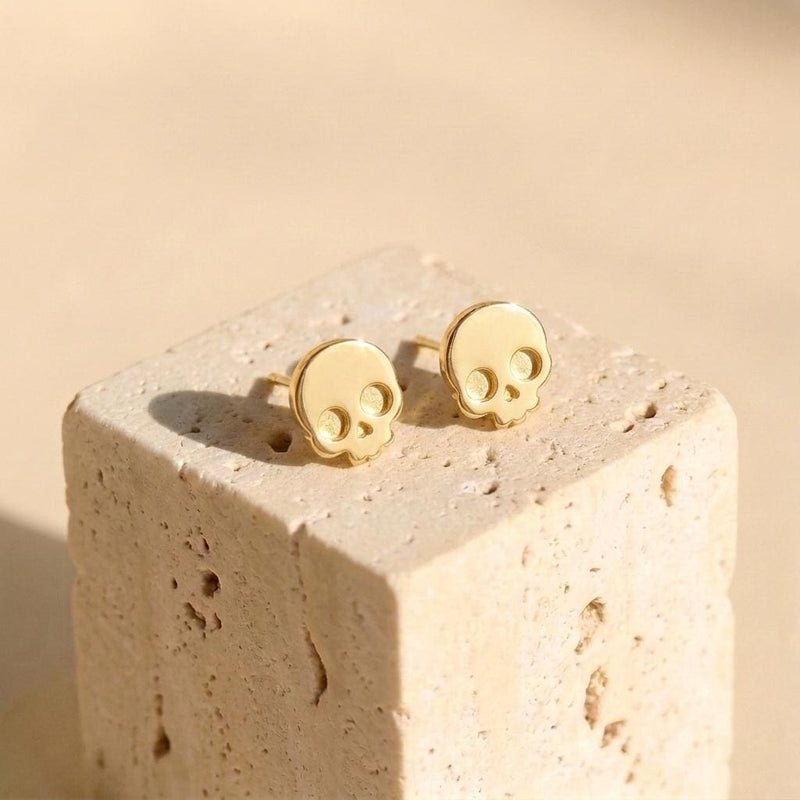 Pair of tiny gold skull stud earrings with round eye sockets