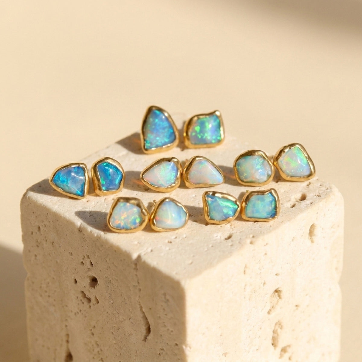Mismatched Tiny Opal Stud Earrings on a travertine block
